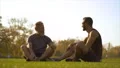 The two happy men sitting on the grass and talking. slow motion 4k or 4k+ Resolution