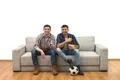 The two happy men watch a football on the sofa on the white background Photo