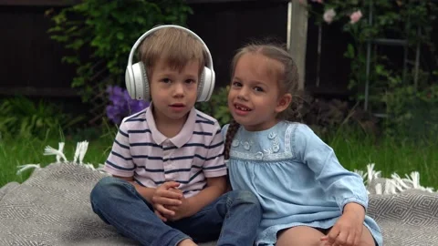 Two Happy Siblings boy ans girl listening to music on headphones outside in Video stock 197463951