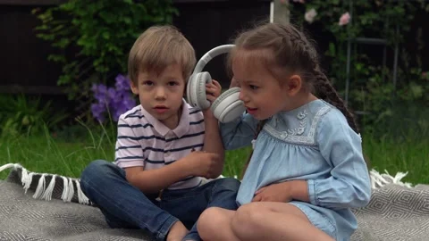 Two Happy Siblings boy ans girl listening to music on headphones outside in Video stock 197852457