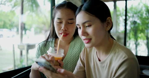Two happy siblings sit at a table playing social media together on smartphone Stockbeeldmateriaal 285010399