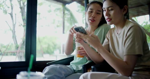 Two happy siblings sit at a table playing social media together on smartphone Stockbeeldmateriaal 285011481