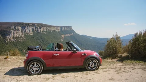 Two happy smiling friends sitting in red cabriolet and enjoying fascinating Stock Footage 108440926
