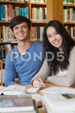 Two happy students in a library Stock Photos
