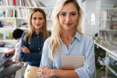 Two happy successful business female collegues standing next to each other in an Stock Photos