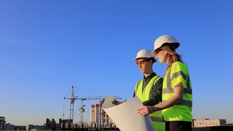 Two happy successful engineers with blueprints in hands discuss the project Stock Footage 105697388