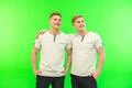 The two happy twin brother stand on the green background Photo
