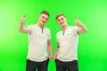 The two happy twin brother thumb up on the green background Photo