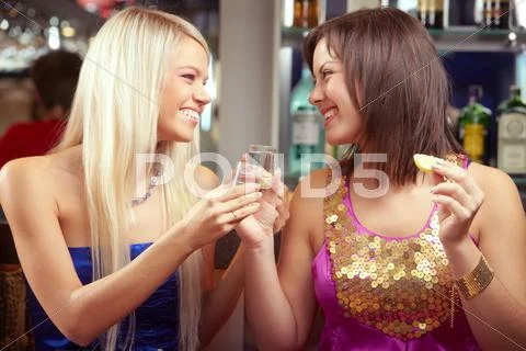 Two happy women drinking alcohol and laughing Stock Photos