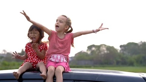 Two happy young kid sitting on top of the car and playing Stock Footage 97698637