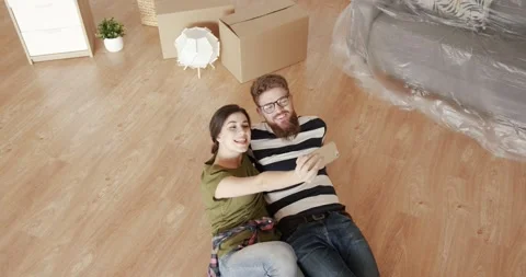 Two happy young people lying on the floor in new apartment and taking selfie on Stock Footage 144630187