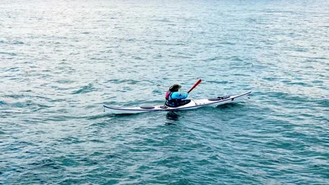 TWO HARBORS, MN - 6 MAY 2025: Person paddles a kayak on the water Stock Footage 318503032