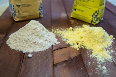 Two heaps of different flour. Yellow one and grey another. Stock Photos