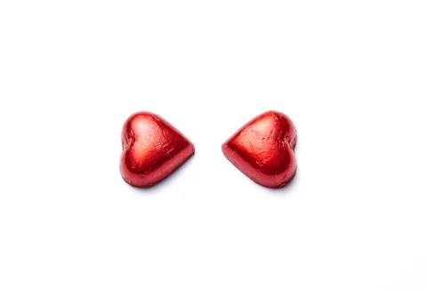 Two heart-shaped chocolates covered with a red paper Stock Photos