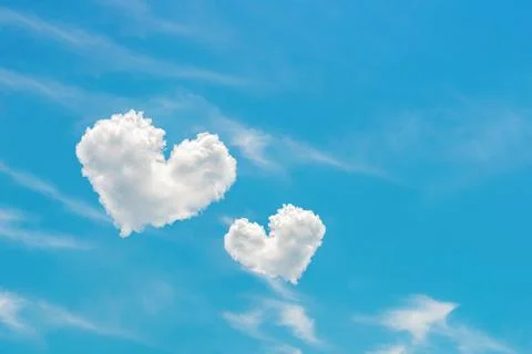 Two heart shaped clouds high in the bright blue sky. Stock Photos
