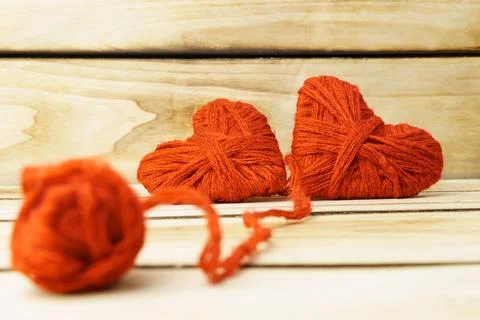 Two hearts and a ball of thread on a wooden background. The hearts are made o Stock Photos