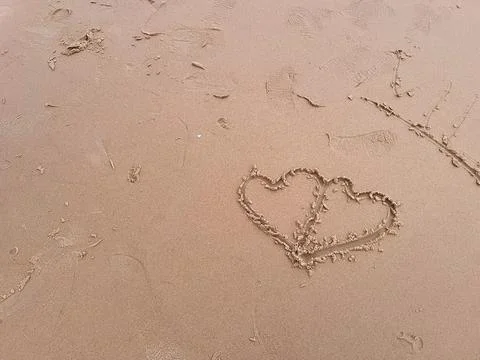 Two hearts drawn on the sand on the beach. Love concept. Stock Photos