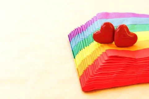 Two hearts lying on a stack of napkins painted under a rainbow on craft paper Stock Photos