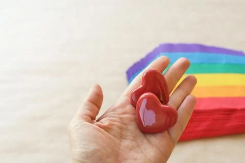Two hearts lying on a stack of napkins painted under a rainbow on craft paper Stock Photos