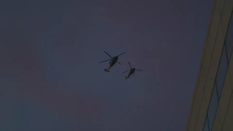 Two helicopters fly close to each other against the background of the sunset Stock Footage 259443614
