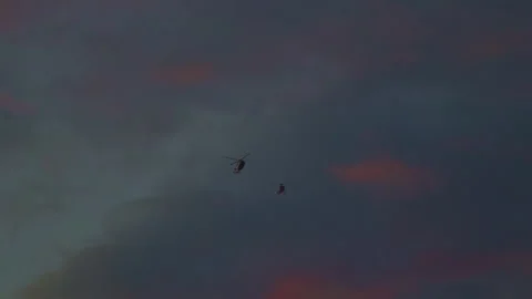 Two helicopters fly close to each other against the background of the sunset Stock Footage 259443664