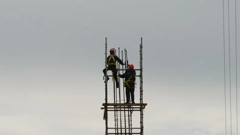 Two high-rise construction workers against the sky. Stock Footage 335245335
