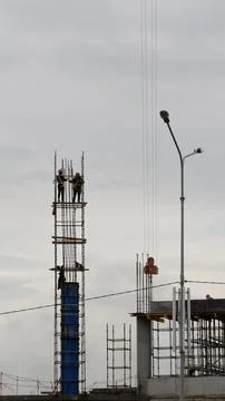 Two high-rise construction workers against the sky. Stock Photos