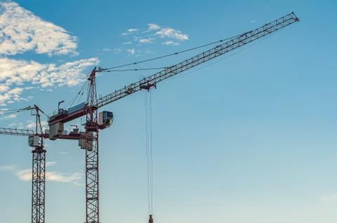 Two high-rise red construction cranes against the blue sky. Stock Photos