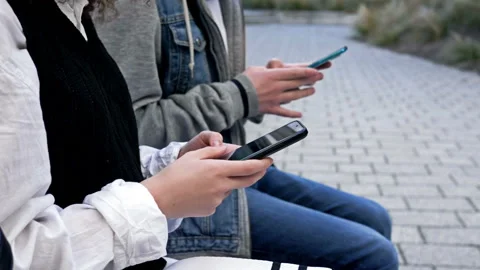Two high school students, a boy and a girl, are sitting on a bench in the school Stock Footage 233367189
