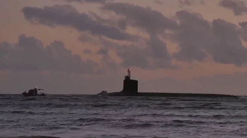 Two high speed boat escort a US Navy nuclear submarine at sunset in Hawaii Stock Footage