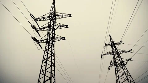 Two high-voltage towers with stretched electrical wires against a gray sky Stock Footage 229448812