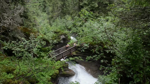 Two hikers on a bridge visit a small waterfall Vídeo Stock 32256230