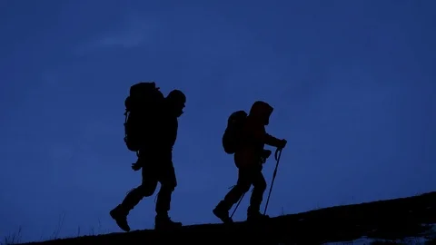 Two hikers going up on the mountain at night with bags of equipment and food. Stock Footage 106770759