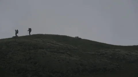 Two hikers going over mountaun ridge in summer. Real time motion Video stock 85391728
