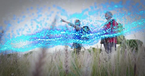 Two hikers in grass pointing and sparking blue particle wave passing under them Stock Footage 327943428
