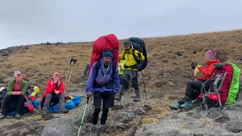 Two hikers with large backpacks walk past a group of campers Stock-Footage 140085838