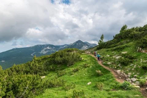 Two hikers in mountains with backpacks on sunny summer day. Stock Photos