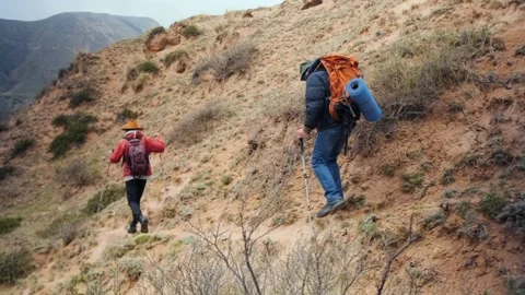 Two hikers moving along steep mountain slope with visible distance between them Stock Footage 333471492