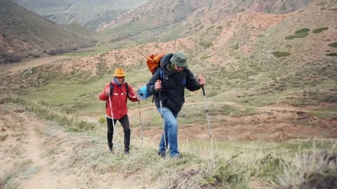 Two hikers moving fast uphill on steep mountain path, pushing pace and competing Stock Footage 333471508