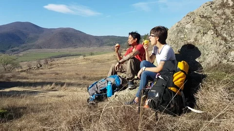Two hikers pause and eat apples in a beautiful landscape in Bulgaria Vídeos de archivo 104825435