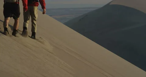 Two hikers on a perfect sand dune in slow motion Vídeo Stock 64332234