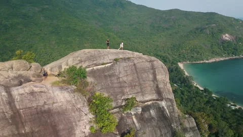 Two hikers stand at edge of steep cliff, enjoying panoramic view of vibrant Stock Footage 312748110