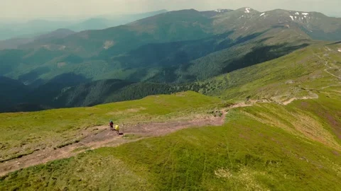 Two hikers standing on top of a mountain with large backpacks. Extremely Stock Footage 158472982