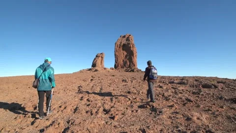 Two hikers walk towards the Roque Nublo. Gran Canaria Stock Footage 136825073