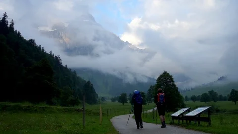 Two hikers walking along a path in the mountains alps Stock Footage 96999484