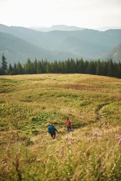 Two hikers walking down a trail together in the mountains Stock Photos