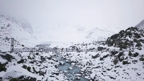 Two hikers walking over bridge with snowy mountain background in New Zealand Stock Footage 121598992