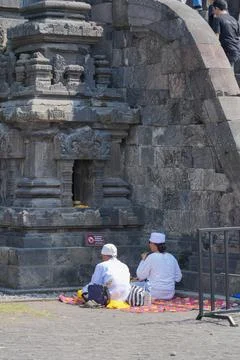 Two Hindus are praying in front of a stone at the Prambanan temple in Indonesia. Stock Photos