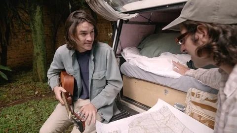 Two hipster men planning a trip together while sitting on a tailgate Video stock 80555410