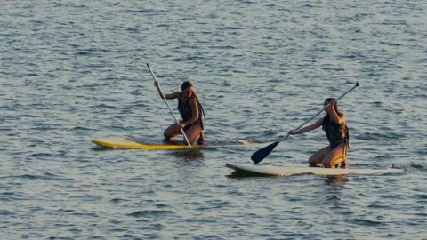 Two hispanic girls rowing with surf boards in Lago Paranoa in Brasilia, Vídeos de archivo 210477572